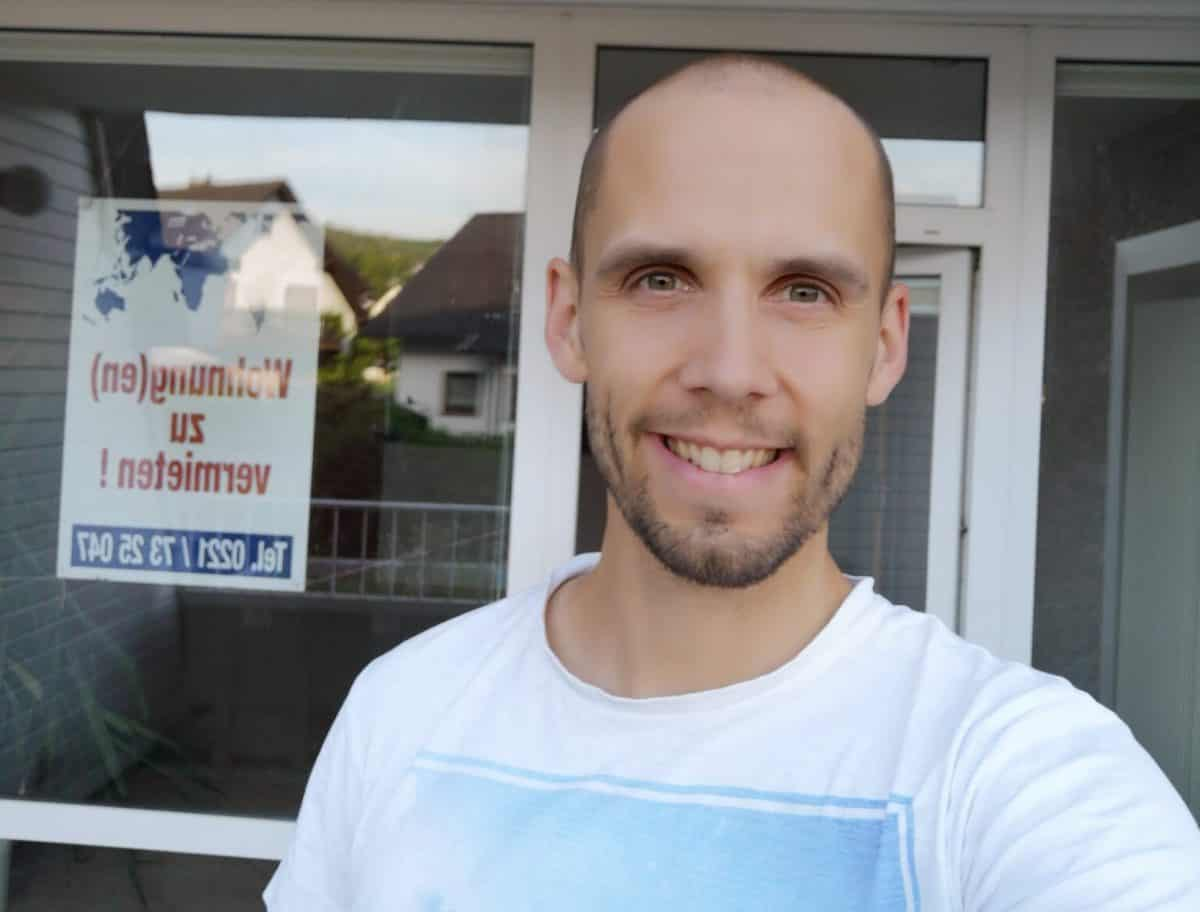 Simon vor einer Wohnung mit Vermietungsschild